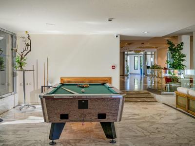 Biljarttafel in een lichte, moderne lounge met zitplaatsen en planten.