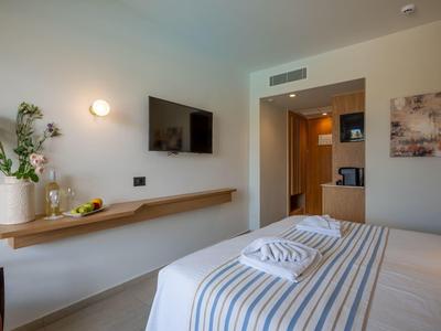 Moderne hotelkamer met bed, wand-tv en bloemen op houten plank.