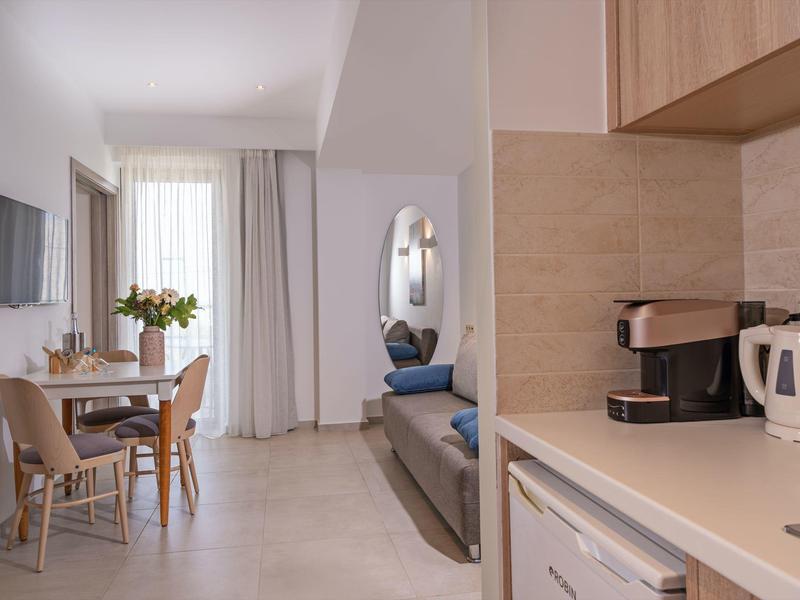 Lichte, moderne keuken- en woonruimte met eettafel, bank en koffiezetapparaat.