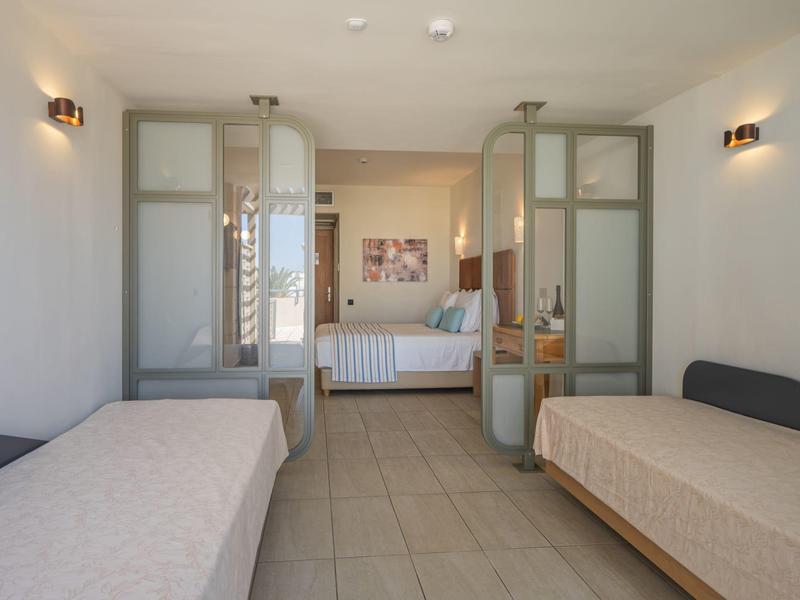 Hotelkamer met twee eenpersoonsbedden, gescheiden door glazen wanden van het tweepersoonsbed.