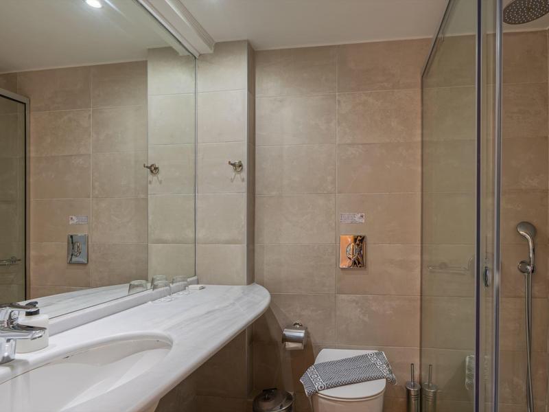 Modern badkamer met grote spiegelwand, dubbele wastafel en glazen douche.