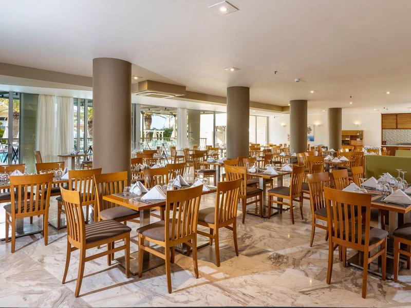 Licht elegant hotelrestaurant met houten tafels en stoelen, gedekt met witte servetten.
