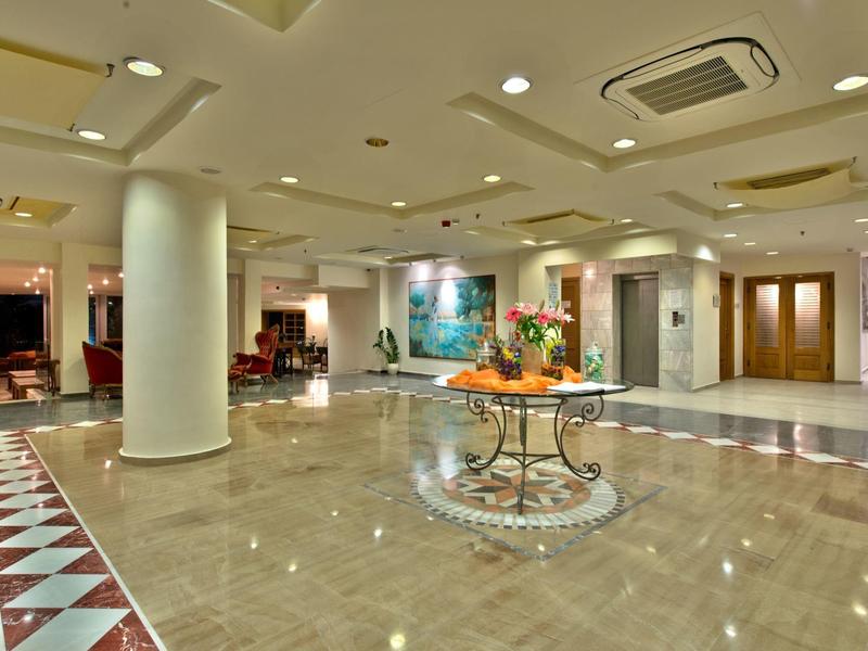 Ruime, lichte hotel lobby met glanzende vloer en decoratieve tafel in het midden.