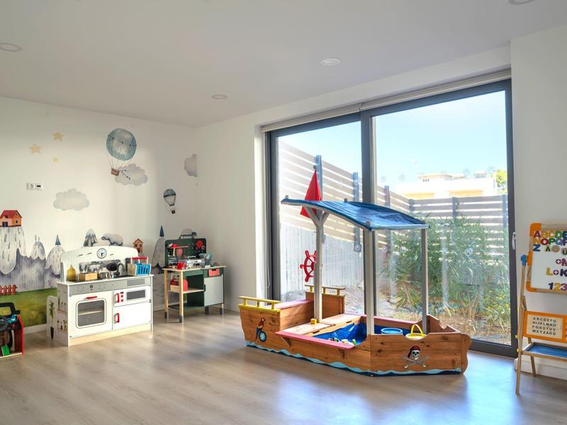 Lichte kinderspeelruimte met houten speelgoed en groot raam.