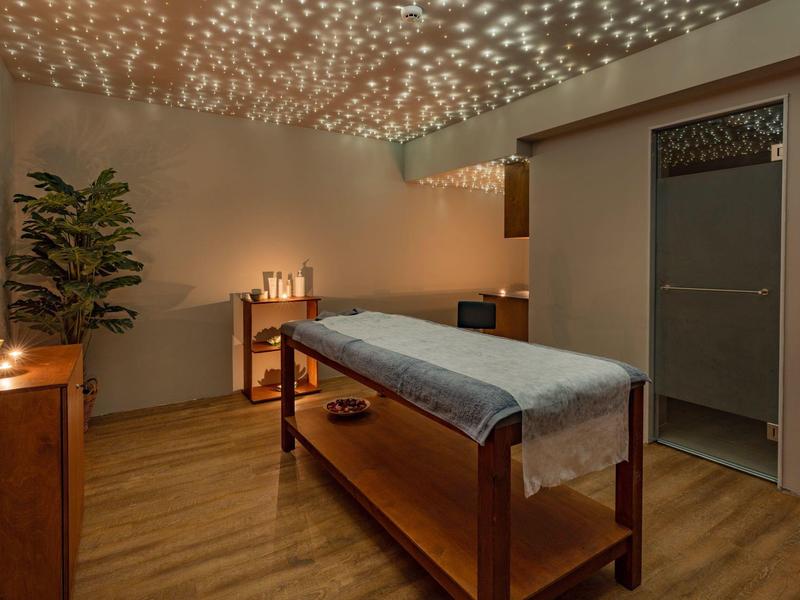 Gezellige massageruimte met houten meubels, plant en sfeerverlichting.