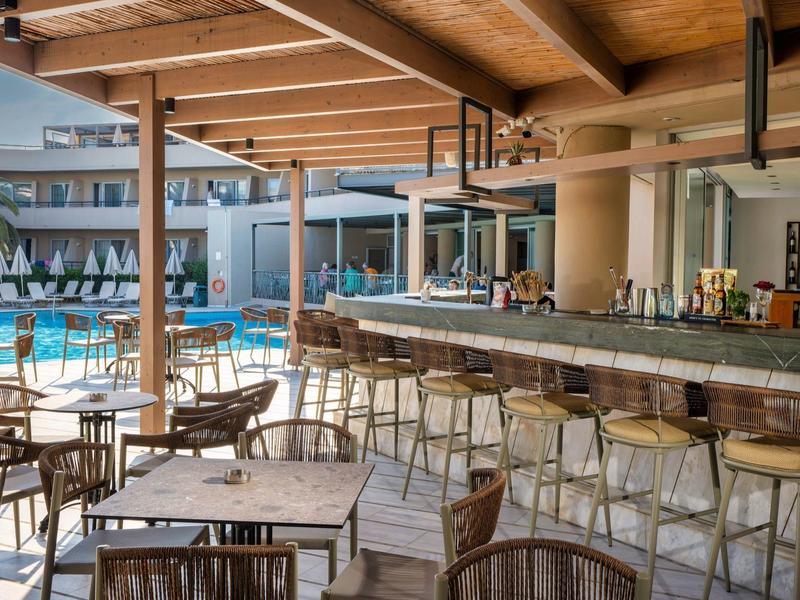 Open hotel zwembadgedeelte met bar, houten dak en zitplaatsen buiten.