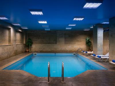 Piscina coperta riscaldata con lettini blu e piante lungo le pareti