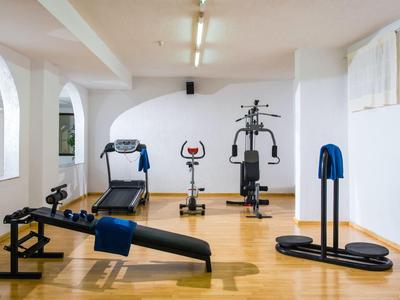 Palestra luminosa con pavimento in legno e varie attrezzature da allenamento contro il muro.