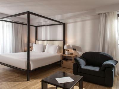 Camera da letto con letto a baldacchino, divano, comodino e grande finestra con tende