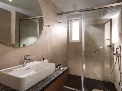 Bagno moderno con lavabo, grande specchio e doccia con parete in vetro.