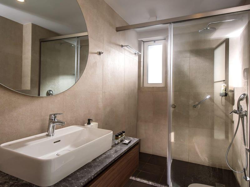 Bagno moderno con lavabo, grande specchio e doccia con parete in vetro.