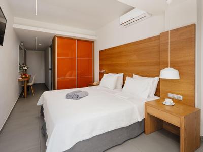 Moderní hotelový pokoj s manželskou postelí, dřevěnými panely a oranžovou skříní