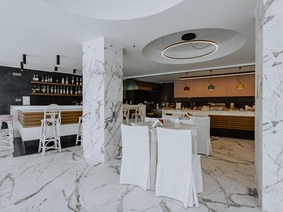 Modernes, elegantes Restaurant mit weißem Marmorboden und stilvollen weißen Stühlen.