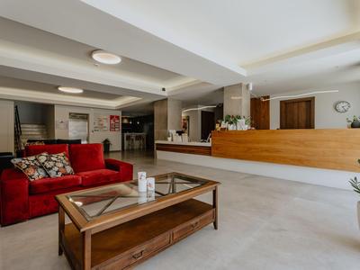 Moderner Hotellobby mit rotem Sofa, Holztisch und Empfangstheke im Hintergrund.