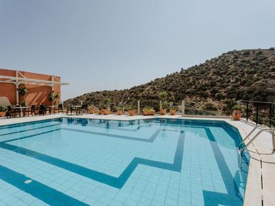 Venkovní bazén s čistou modrou vodou u kopce pod jasnou oblohou