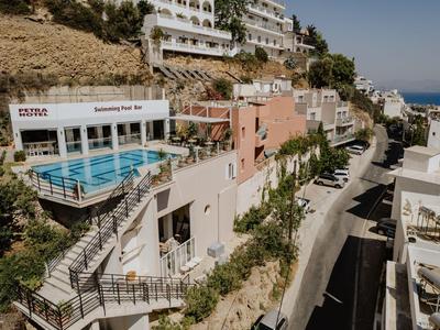 Hotelanlage mit Pool auf einem Hügel, umgeben von Gebäuden und Blick auf das Meer.