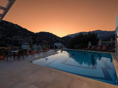 Poolbereich eines Hotels bei Sonnenuntergang mit Berglandschaft im Hintergrund.