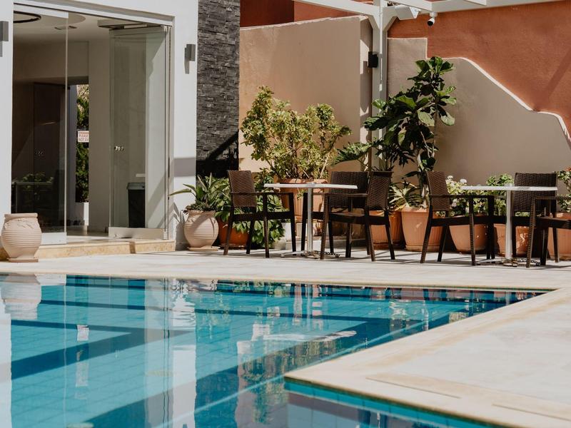 Moderní venkovní bazén s modrými dlaždicemi a posezením s stolem a rostlinami.