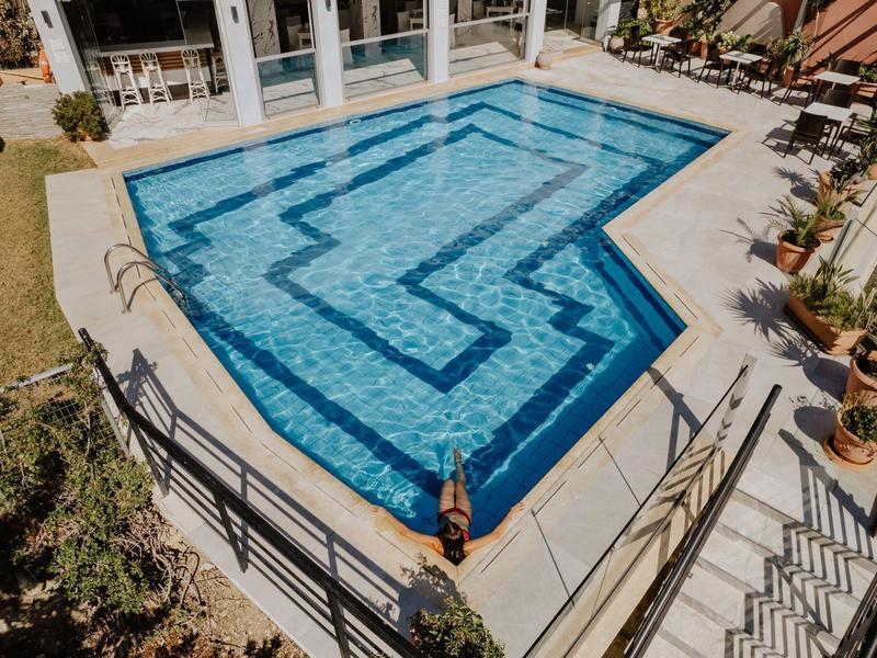 Moderní bazén s geometrickým vzorem a posezením v hotelovém venkovním prostoru.