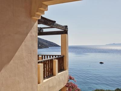 Terrace with railing on a beige building overlooking calm, blue sea water surface.
