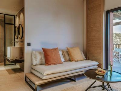 Modern furnished room with sofa, table, and balcony overlooking the sea.