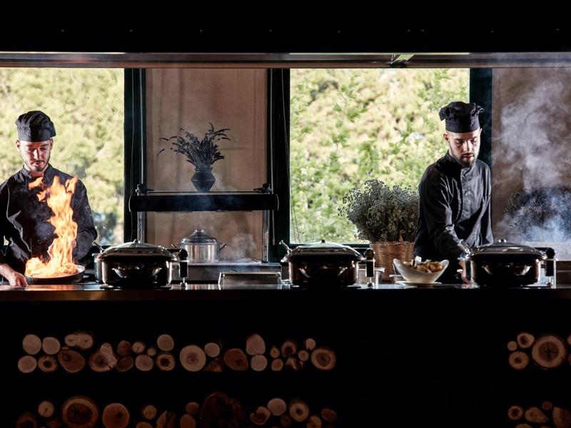 Two chefs working in an open kitchen with visible flames and steam.