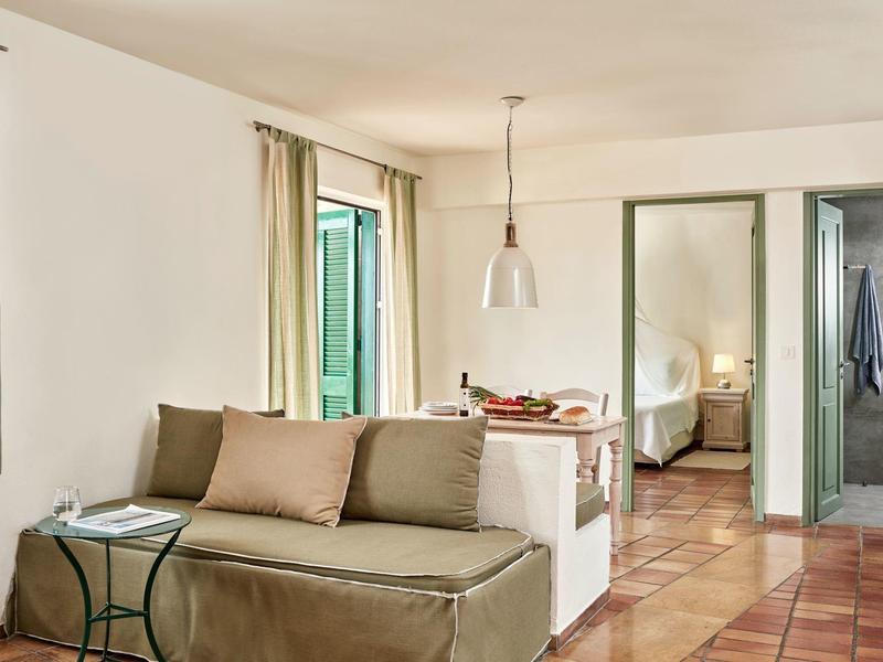 Cozy seating area with sofa, cushions, and small table in a bright hotel room.