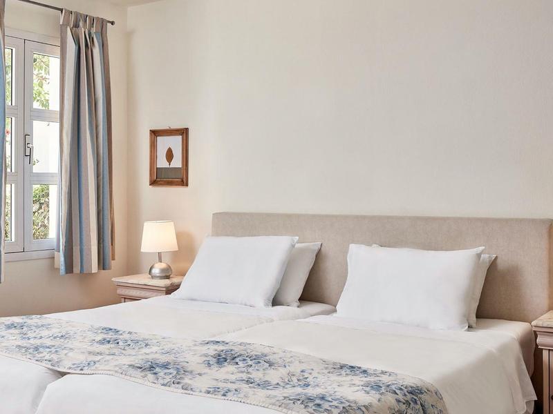 Hotel room with two beds, white bedding, bedside lamps, and window with curtains.