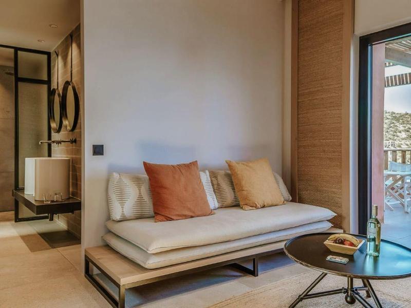 Modern furnished room with sofa, table, and balcony overlooking the sea.