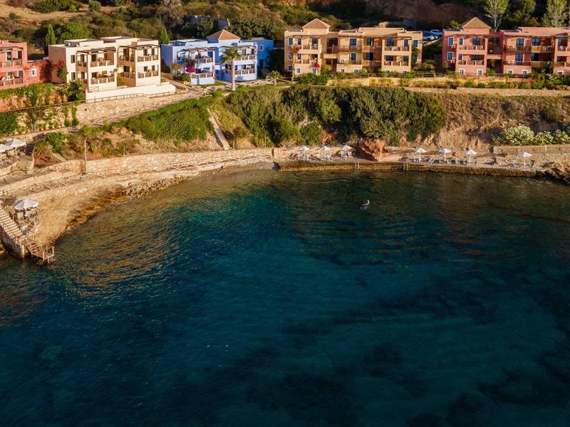 Seaside village with colorful houses by a calm bay and clear dark blue water.