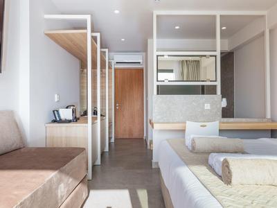 Jasny pokój hotelowy z łóżkiem, sofą i dużą drewnianą komodą