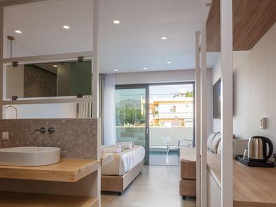 Nowoczesny pokój hotelowy z otwartą łazienką, łóżkiem i balkonem z widokiem na zewnątrz.