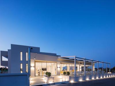 Moderní osvětlený dům s velkou terasou a posezením za soumraku.