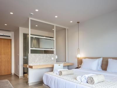 Moderní hotelový pokoj se dvěma postelemi, dřevěnými doplňky a světlým, minimalistickým zařízením.