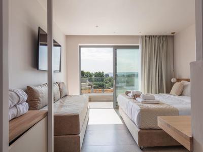 Nowoczesny pokój hotelowy z łóżkiem, sofą, telewizorem i balkonem z widokiem na morze.