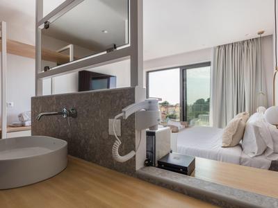 Nowoczesny pokój hotelowy z umywalką, dużym oknem i widokiem na przyrodę.