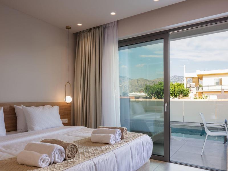 Jasny pokój hotelowy z łóżkiem podwójnym i dostępem do balkonu z widokiem.