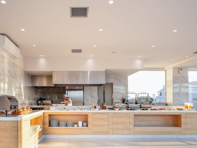 Nowoczesna kuchnia z drewnianymi szafkami i dużymi oknami, jasne wnętrze.