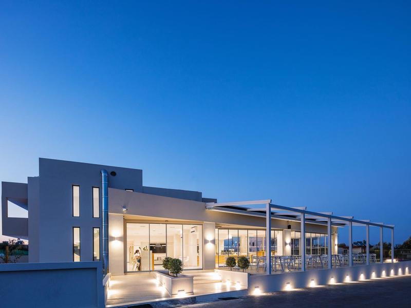 Nowoczesny, oświetlony dom wakacyjny z dużym balkonem pod jasnym, niebieskim wieczornym niebem.