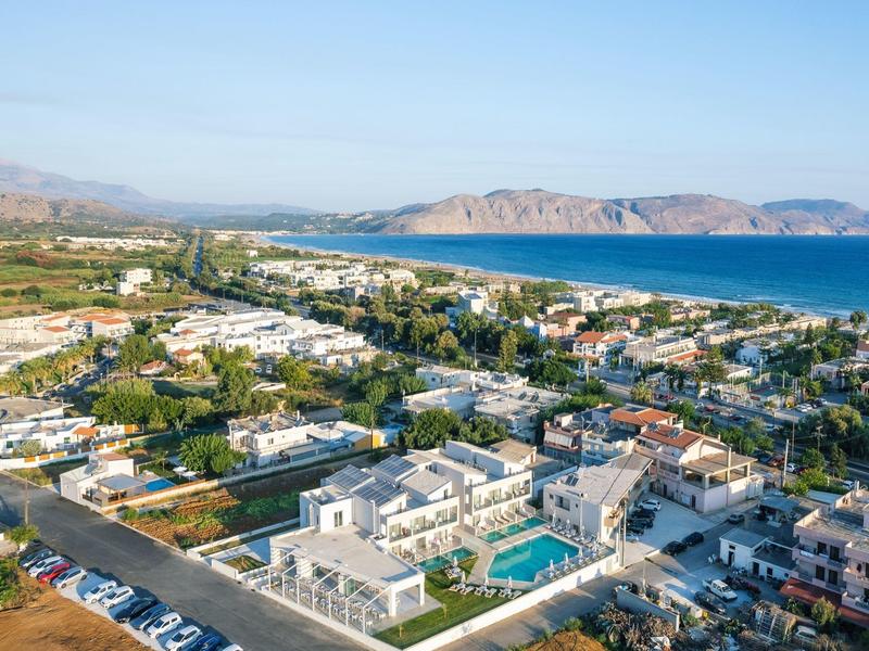 Widok z lotu ptaka na nadmorskie miasto z hotelami, górami w tle i błękitnym niebem.