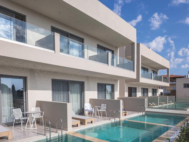 Nowoczesny kompleks hotelowy z rzędami pokoi i prywatnym basenem pod niebieskim niebem.