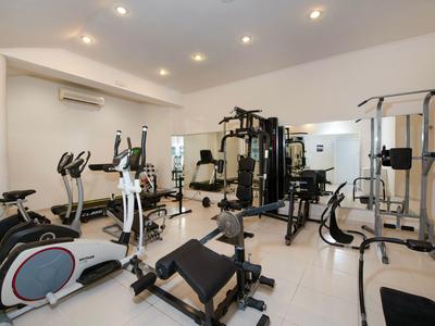 Heller Fitnessraum mit verschiedenen Trainingsgeräten und neutralen Wänden.