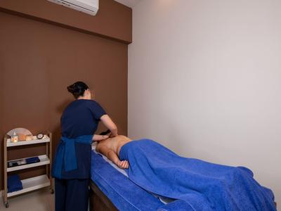 Eine Massage im Spa-Zimmer mit blauem Bett und behandelnder Person.