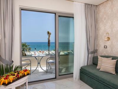 Camera d'hotel moderna con vista mare, balcone, divano e elementi decorativi.