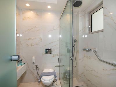 Bagno d'hotel moderno con toilette, cabina doccia e pareti effetto marmo.