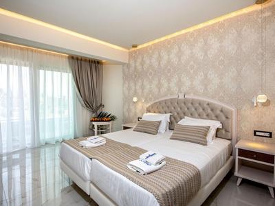 Elegante camera d'hotel con letto grande, parete decorativa e luce naturale da ampie finestre.