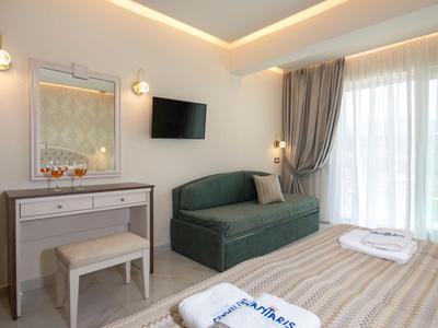 Camera d'hotel moderna con divano, TV, tavolo da trucco e grande finestra con tende.