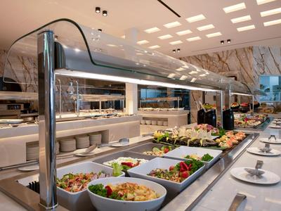 Area buffet con varie insalate e piatti caldi in un ristorante moderno di un hotel.