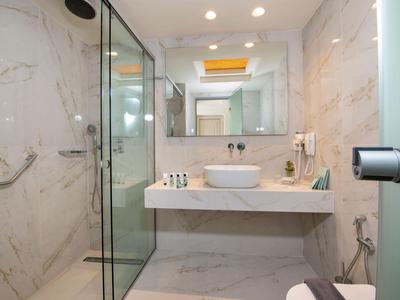 Bagno d'hotel moderno con pareti in marmo, grande specchio e doccia in vetro.