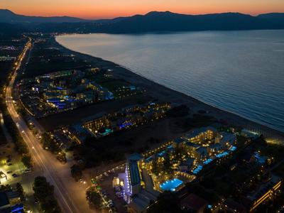Una città costiera con strade illuminate e hotel sul mare al tramonto.